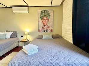 Ein Hotelzimmer mit zwei Betten, einem Bild an der Wand, einer Lampe und einem gefalteten Handtuch auf dem Bett.