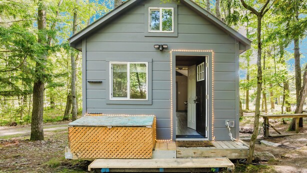 A small cabin with a porch, a door, and a window. - Tiny House (Nobel)