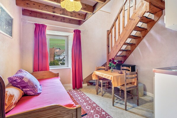 Un dormitorio con cama, escritorio, silla, ventana con cortinas y una escalera.