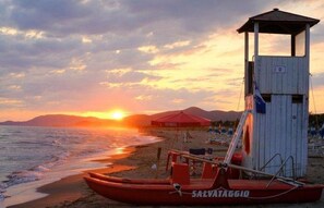 A lifeguard tower, a red lifeboat, and a beach umbrella.