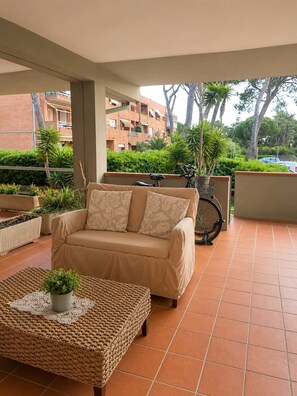 A covered outdoor seating area with a sofa, a wicker table, and a bicycle. - A breath of 50m from the sea (grosseto)