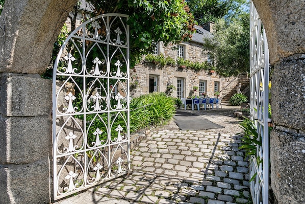 A stone building with a cobblestone pathway leading to a gated entrance.
