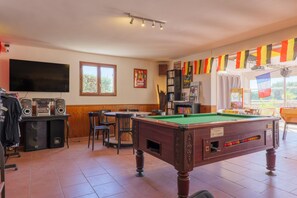 Une table de billard, un téléviseur et un coin bar équipé d’une table de billard.
