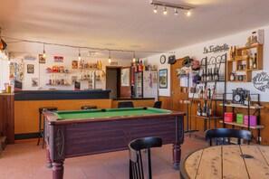 Un espace bar équipé d’une table de billard, de chaises et d’étagères remplies de bouteilles.