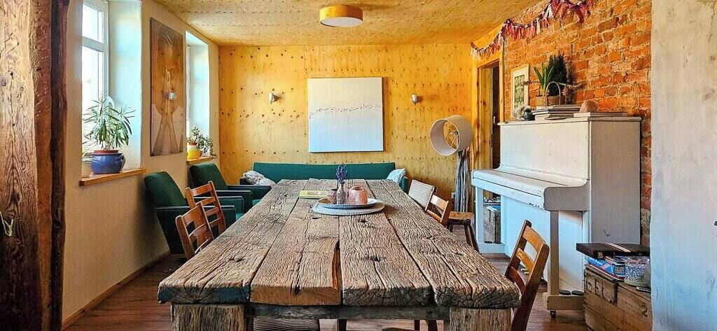 Un coin repas rustique avec une table en bois, des chaises et un canapé vert.