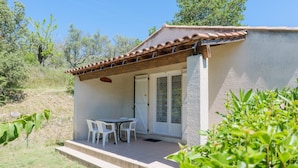 A small building with a tiled roof, a covered patio with a table and chairs, and a door leading to an interior space. - Gite Le Micocoulier La Fontinelle – Modern Holiday Home in Peaceful Ardèche Nature (Bessas)