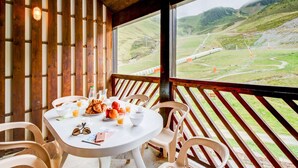 Une cabane en bois avec une table ronde dressée pour le petit-déjeuner, offrant une vue sur un paysage montagneux.