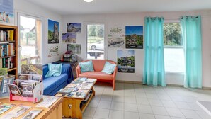 A room with a sofa, a coffee table with brochures, a bookshelf, and a window with curtains. - Relaxed Family Home in Egletons (Egletons)