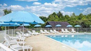 A swimming pool with white lounge chairs and blue umbrellas. - Relaxed Family Home in Egletons (Egletons)