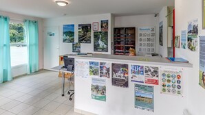 A reception area with a counter, informational posters, and a window with curtains. - Relaxed Family Home in Egletons (Egletons)
