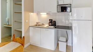 A compact kitchen with white cabinets, a microwave, a refrigerator, a sink, and a coffee maker. - Relaxed Family Home in Egletons (Egletons)