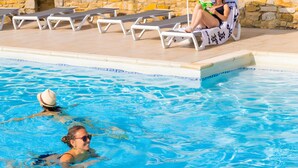 A swimming pool with lounge chairs, a stone wall, and a building in the background. - Holiday Home “Le Cyprès - La Fontinelle” (Bessas)