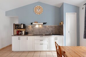 Een kleine keuken met witte kasten, een inbouwoven en een magnetron.