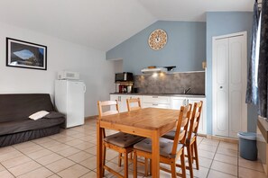 Ein gemütlicher Wohnbereich mit Küchenzeile, einem Esstisch mit Stühlen, einer Couch und einem gerahmten Bild an der Wand.
