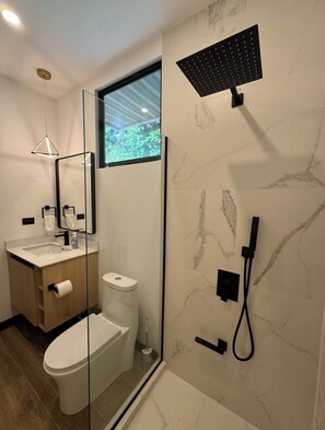 A modern bathroom with a glass-enclosed shower, a toilet, a sink with a mirror, and a window providing natural light. - AO Buena Vista Private Mountain Retreat (Concepción)