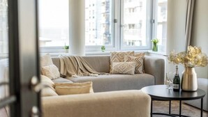 Ein modernes Wohnzimmer mit einer Couch, einem runden Couchtisch und einer Vase mit Blumen.