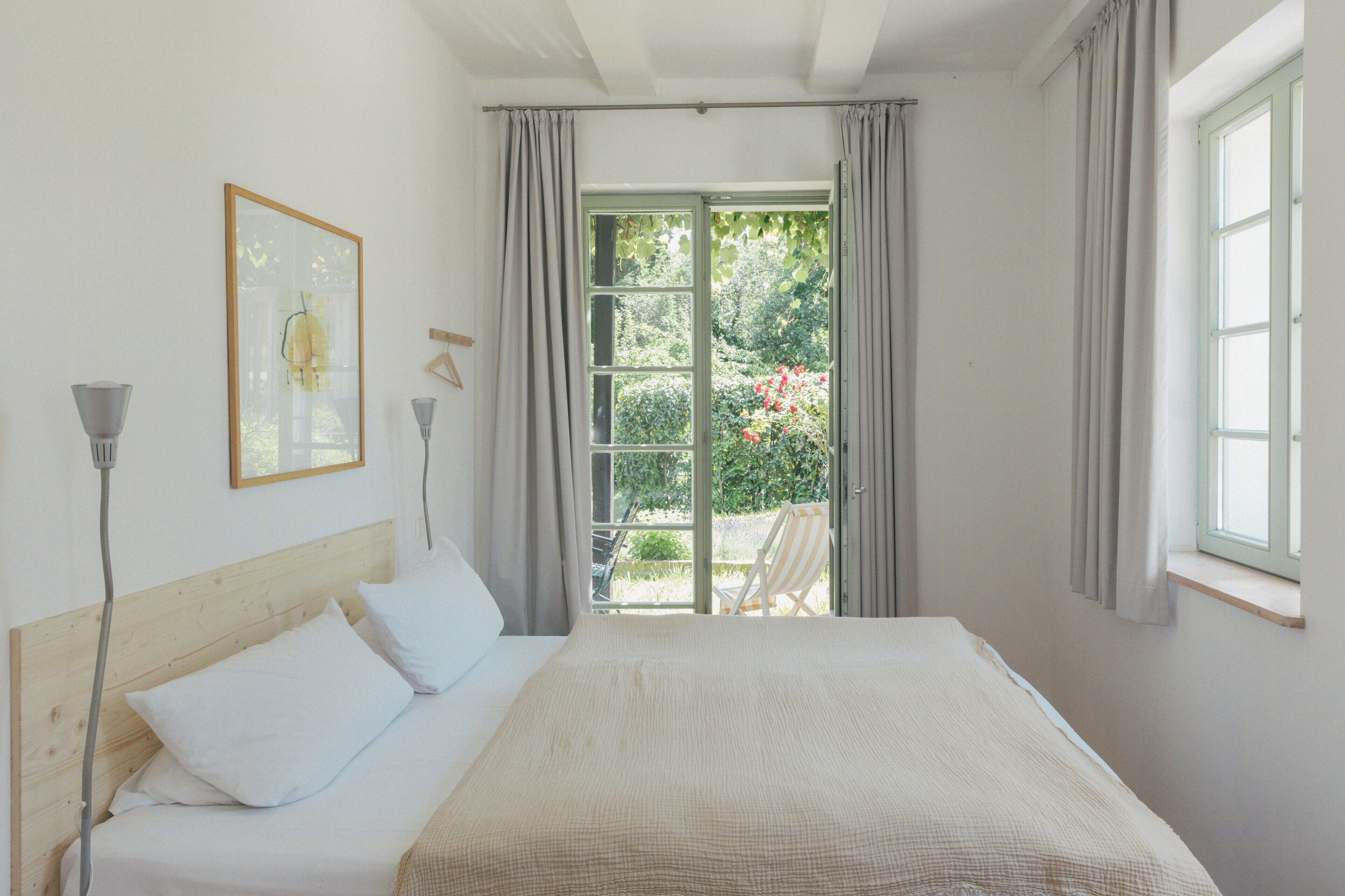 Ein Schlafzimmer mit Bett, Fenster und Gartenblick.