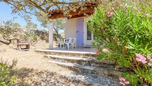A stone staircase leading to a covered outdoor seating area with white plastic chairs and a table.