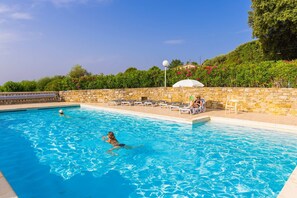 En swimmingpool med liggestole og en stenvæg.