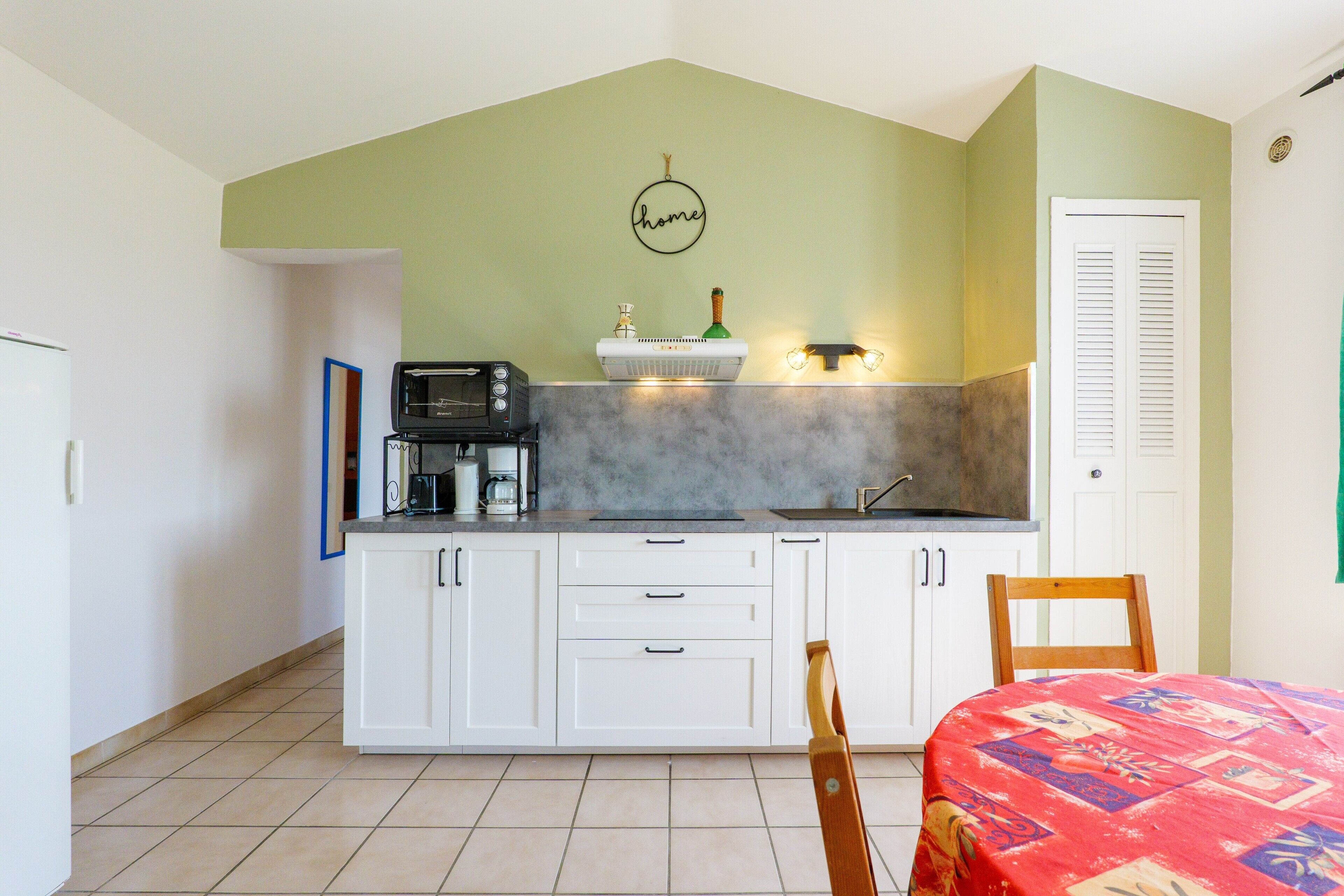 A kitchen with white cabinets, a microwave, a coffee maker, and a sink.