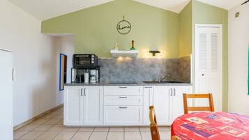 A kitchen with white cabinets, a microwave, a coffee maker, and a sink.