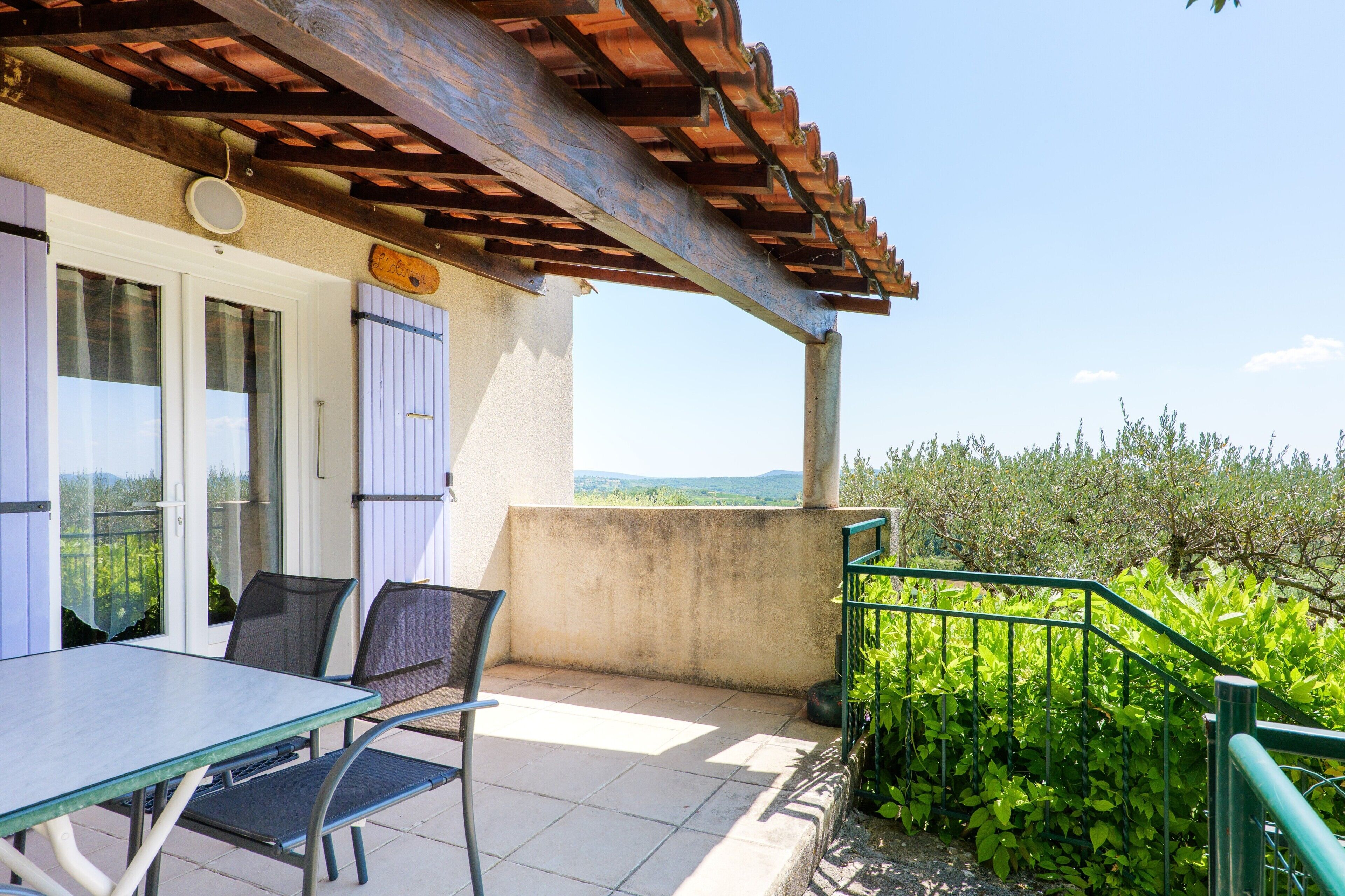 A terrace with a table and chairs, a pergola, and a view of greenery.