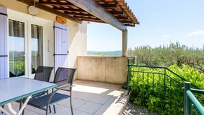 A terrace with a table and chairs, a pergola, and a view of greenery. - Holiday Home “L’Olivier - La Fontinelle” (Bessas)