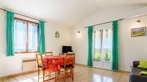 A dining area with a table, chairs, a television, and a sofa. - Holiday Home “L’Olivier - La Fontinelle” (Bessas)