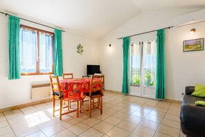 A dining area with a table, chairs, a television, and a sofa. - Holiday Home “L’Olivier - La Fontinelle” (Bessas)