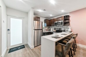 Une cuisine moderne dotée d’appareils électroménagers en acier inoxydable, de meubles en bois et d’un bar pour prendre le petit-déjeuner.