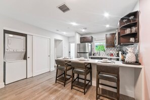 A modern kitchen with a central island, bar stools, a built-in oven, and a stainless steel refrigerator. - Boca Raton Apartment with King Bed Across the Beach. Near Mizner Park. (Boca Raton)