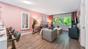Uma sala de estar moderna com área de jantar, um espelho grande e vista para o verde lá fora.