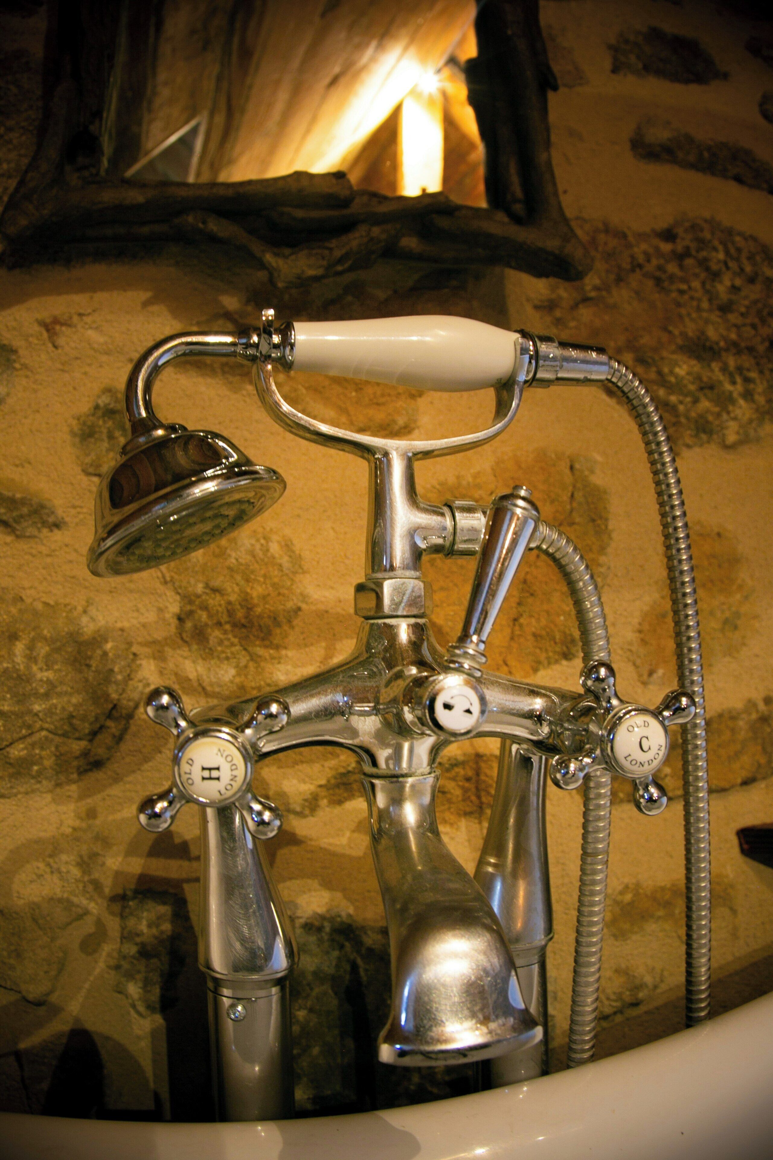 A vintage-style bathroom with a clawfoot bathtub, a showerhead, and a faucet with a hose.
