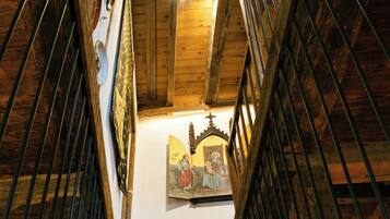 A wooden staircase with metal railings leading to a room with a framed artwork on the wall.