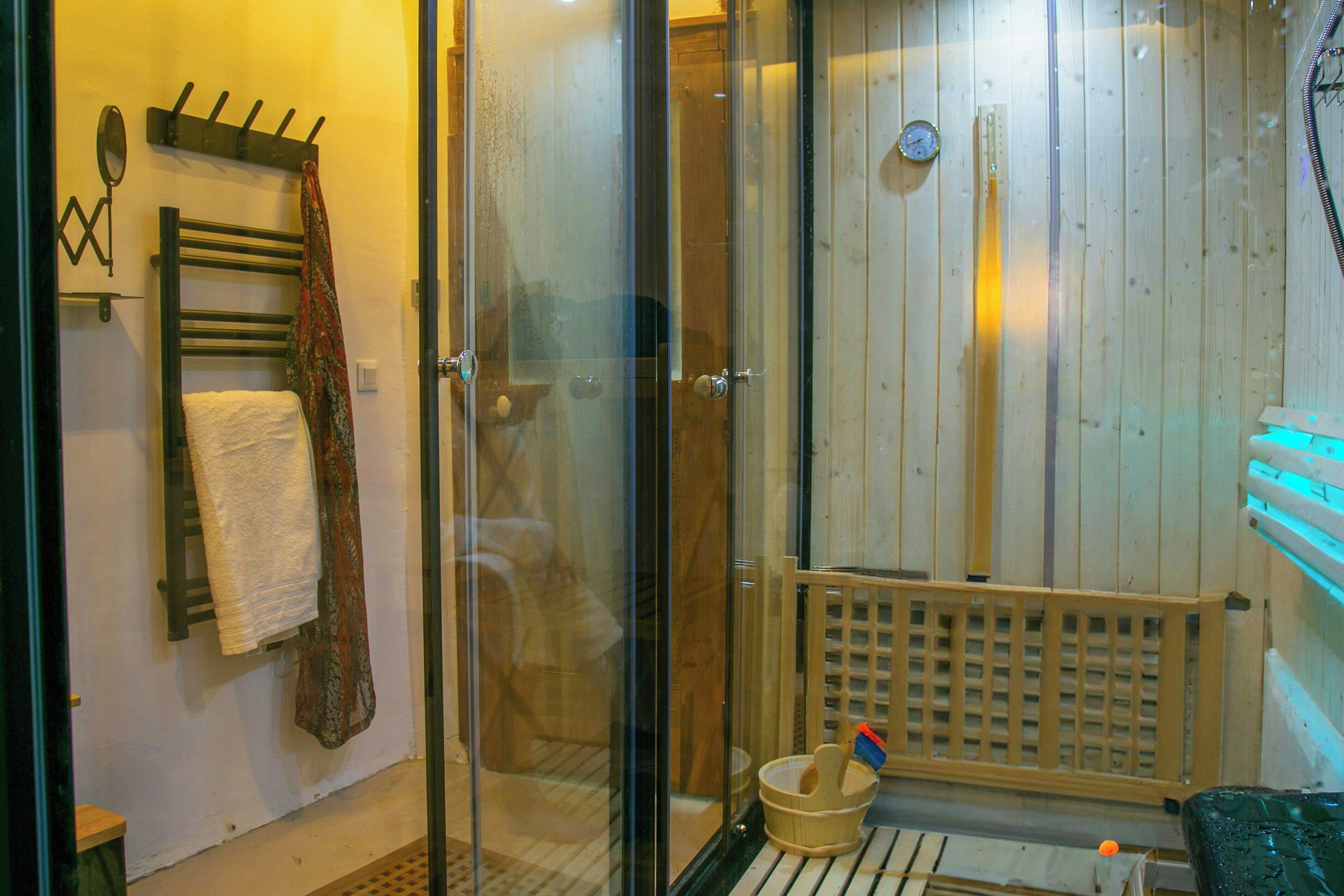 Eine Sauna mit Glasfront, einer hölzernen Sitzbank, einem Handtuchhalter und Holzboden.