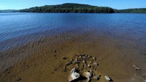 A clear lake with a rocky shoreline and a forested island in the distance. - Twin houses on the Plateau de Millevaches (Croze)