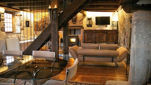 A cozy living room with a fireplace, sofas, and a glass coffee table. - Twin houses on the Plateau de Millevaches (Croze)
