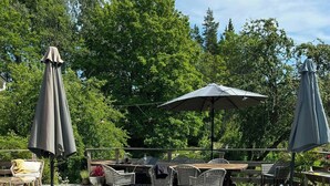 Eine Holzterrasse mit Pool, Gartenmöbeln und Sonnenschirmen.