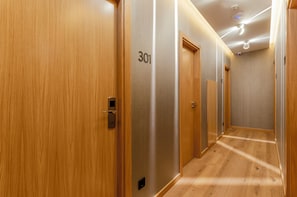 A hallway with wooden doors, numbered 301 and 302, and a modern ceiling with recessed lighting. - Ouro Rossio Hotel (Lisbon)