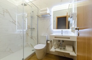 Un bagno moderno con box doccia in vetro, un water, un lavandino con specchio e una porta in legno.
