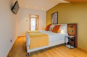 Una camera d'albergo moderna con un letto, un comodino e una televisione a muro.