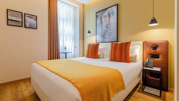Una habitación de hotel con una cama, un escritorio con teléfono y una ventana con cortinas.