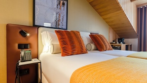 Habitación de hotel con cama, mesita de noche, teléfono y un cuadro en la pared.