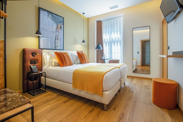 A hotel room with a bed, bedside table, lamp, and a mirror on the wall. - Ouro Rossio Hotel (Lisbon)