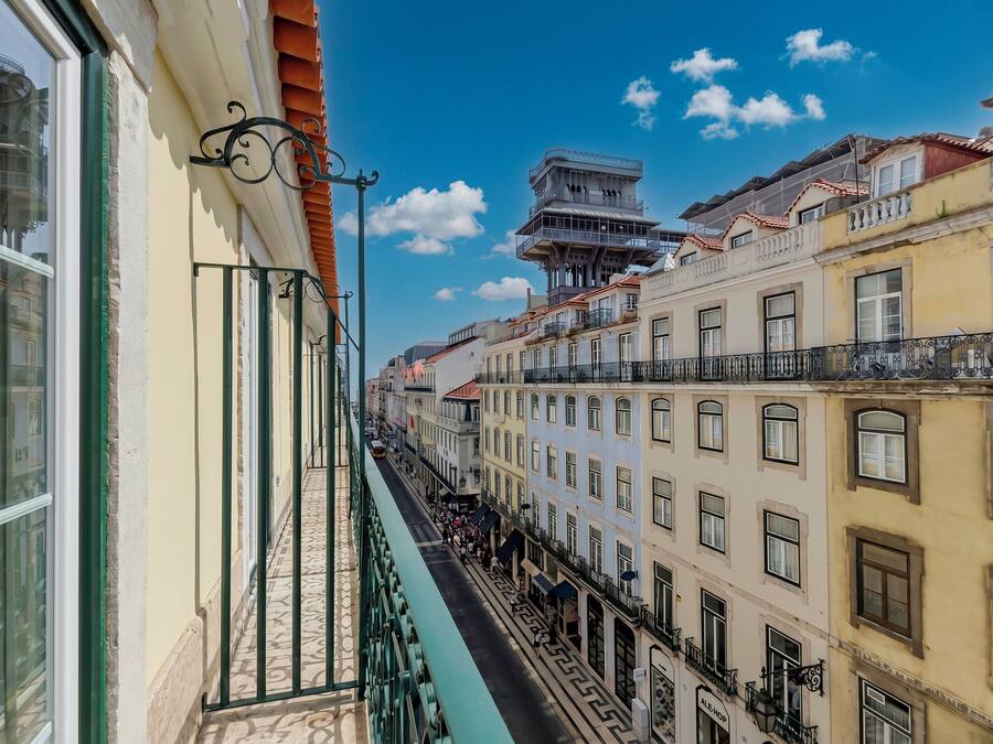 Una calle estrecha bordeada por edificios de varios pisos con balcones, cielo despejado y una acera para peatones.