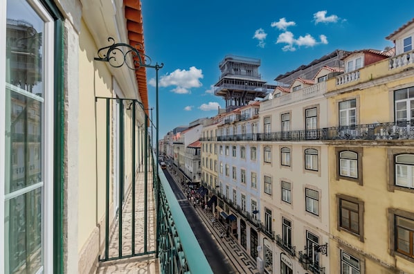 A narrow street flanked by multi-story buildings with balconies, a clear sky, and a pedestrian walkway. - Ouro Rossio Hotel (Lisbon)
