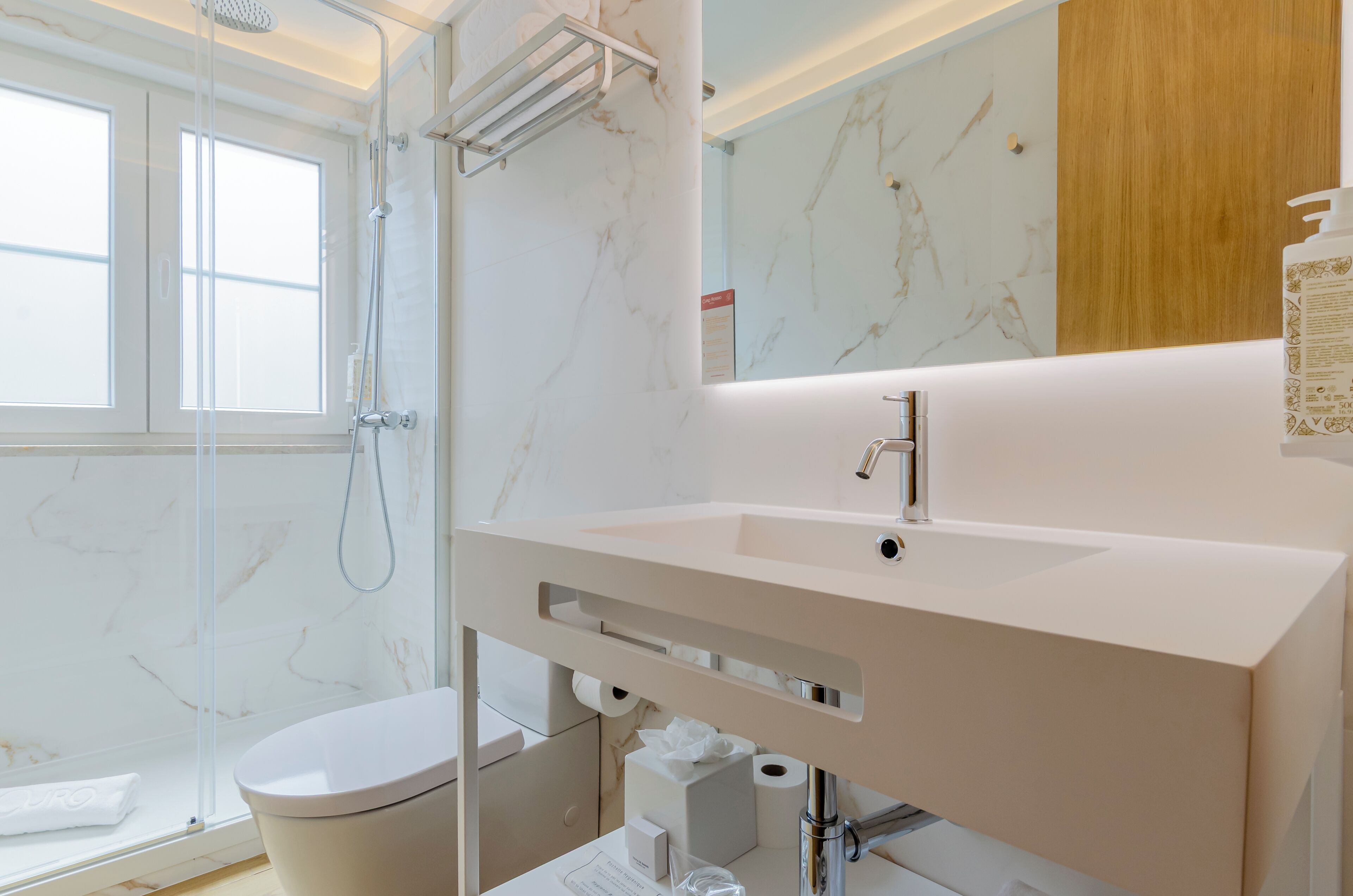 A modern bathroom with a white sink, a mirror, and a shower.