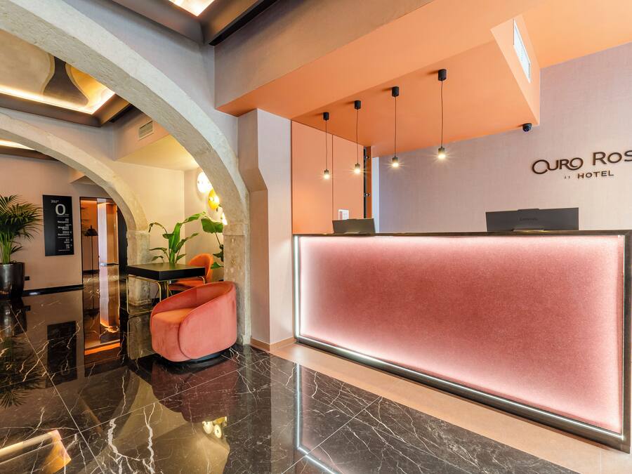 A hotel reception area with a marble floor, a reception desk, and a sign for 'Auro Rossio Hotel'.