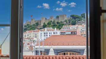 Una vista di un castello storico su una collina, con uno skyline urbano in primo piano.