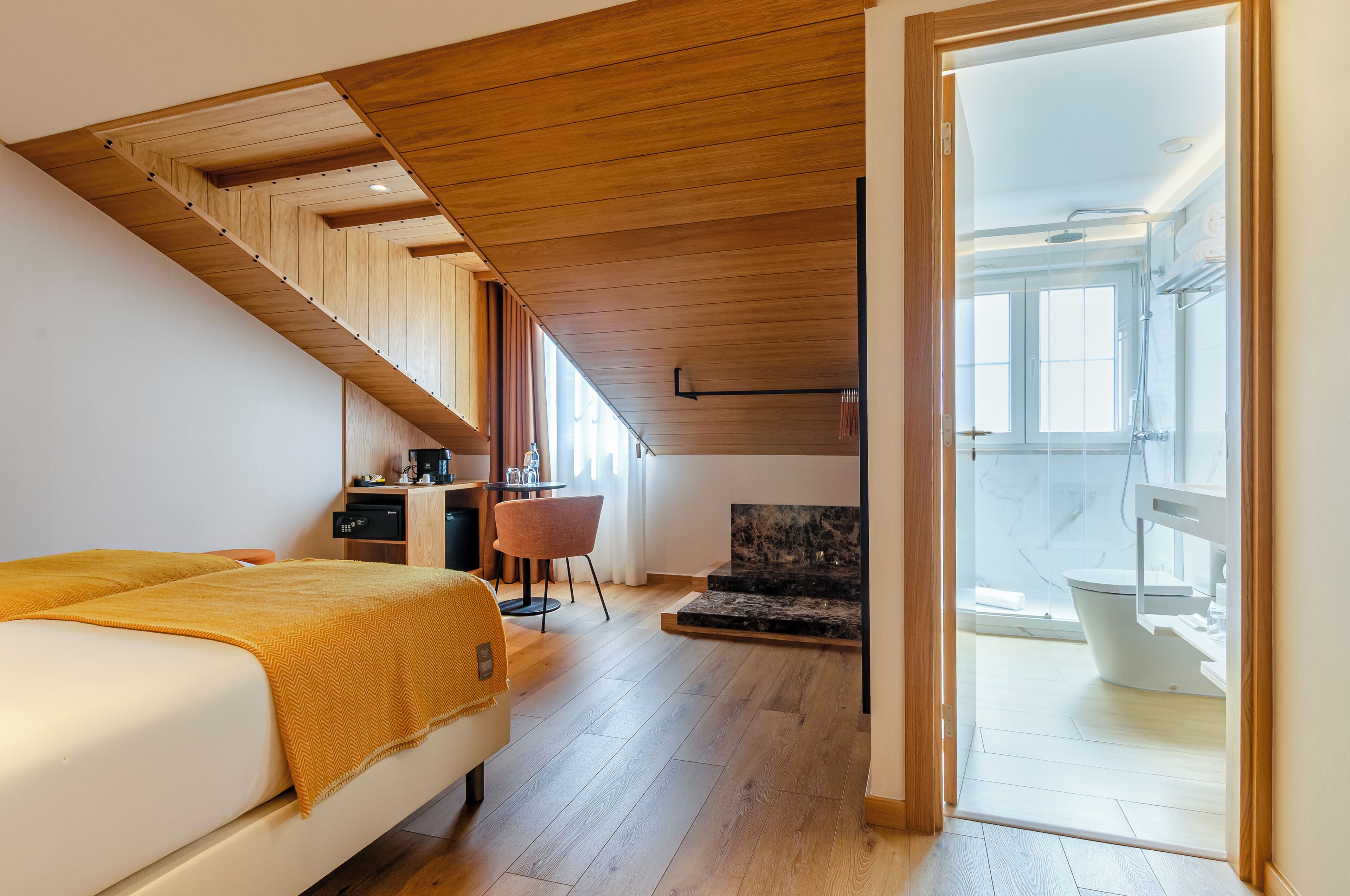 Un dormitorio con cama, escritorio, silla y vistas al baño.